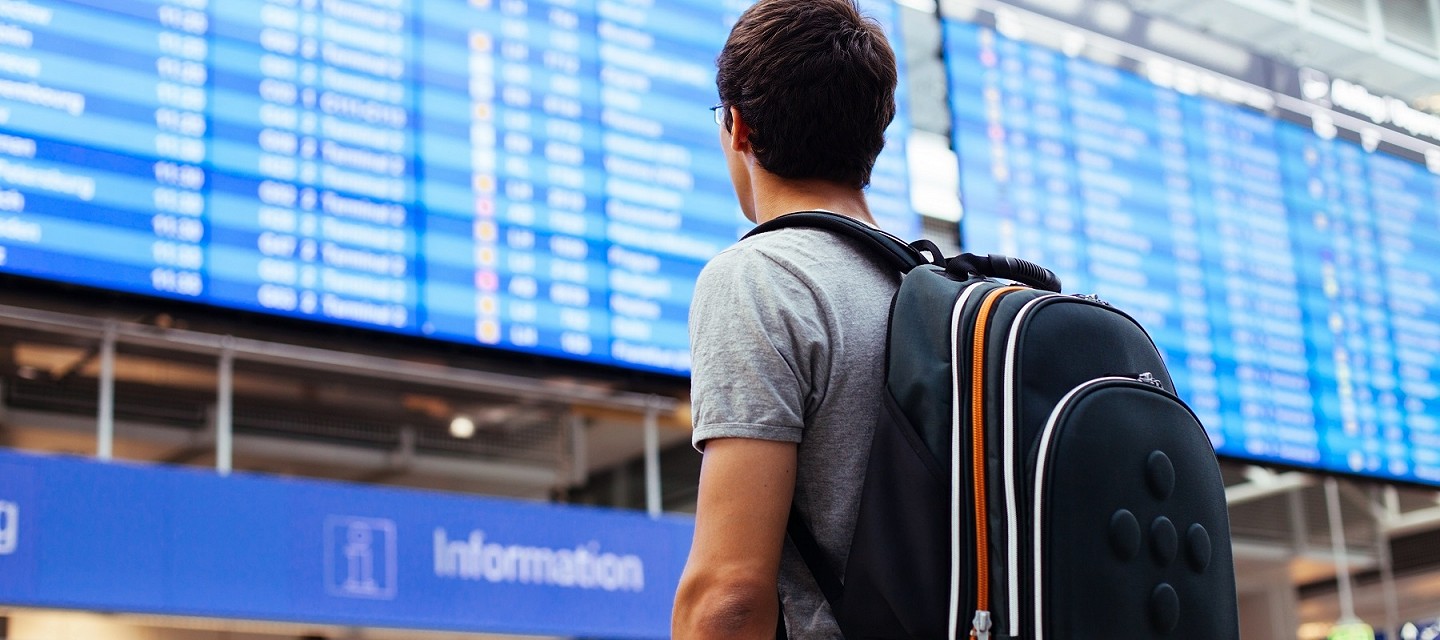 man looking at departure list at airport